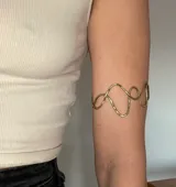 Brazalete rígido plateado con diseño irregular de ondas.