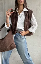 Chaleco de gamuza color chocolate con interior y bordes de corderito sintético. Presenta diseño con tachas metálicas decorativas en el frente y los hombros.