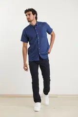 Camisa azul de manga corta, con cuello abotonado y bolsillo en el pecho.