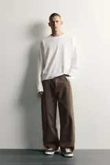 Pantalón barrel fit de mezclilla color verde militar, con efecto lavado, cinco bolsillos, cierre frontal con cremallera y botón, y detalle de pinzas en las rodillas.
