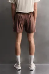 Short deportivo de entrenamiento en color marrón, confeccionado en tejido técnico ligero y elástico. Cuenta con cintura elástica ajustable con cordón, bolsillos frontales, bolsillo trasero con cierre y aberturas laterales en el bajo. Incluye un pequeño detalle de logo estampado en la pierna.