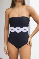 Traje de baño entero negro con breteles finos y detalle de recorte con forma de ondas en la cintura.