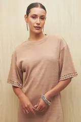 Vestido corto color rosa nude de punto, con mangas cortas y apliques de tachas plateadas en las terminaciones de las mangas.