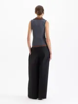 Pantalón negro de poplín asargado, corte holgado y tiro alto con pliegues frontales. Presenta un cruce en la cintura que genera un cinturón con gancho.