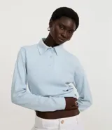 Blusa tipo polo de manga larga, confeccionada en tejido interlock de algodón y poliéster. Presenta cuello clásico con cierre frontal de botones y diseño básico liso.