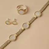 Anillo de diseño circular con centro de nácar y borde texturizado en tono dorado, montado sobre una banda de plata.