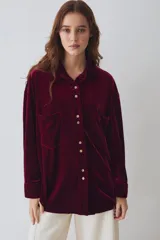 Camisa de terciopelo color bordó, de corte oversize, con mangas largas, bolsillos frontales con solapa y cierre de botones.