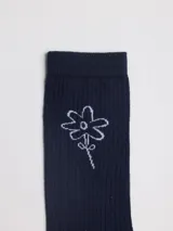 Medias de caña media en color azul marino, con textura acanalada y un pequeño diseño bordado de una flor en color blanco.