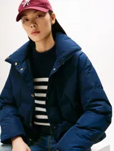 Campera acolchada de corte regular con cuello chimenea, cierre frontal a presión con botones dorados y bolsillos laterales. Presenta un diseño repelente al agua con relleno de plumón y escudo de la marca bordado en el pecho.