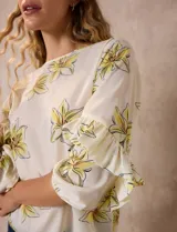 Blusa de gasa estampada con flores azules y violetas sobre fondo blanco, de manga 3/4 con volados.