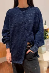 Camisa de punto azul con diseño de rombos calados y destellos plateados, de corte holgado, manga larga con puños ajustados y cierre frontal de botones.