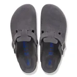 Zuecos tipo mule de gamuza en color gris carbón, con tira ajustable con hebilla metálica, plantilla de corcho y suela de goma negra.