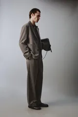 Pantalón de traje wide fit color marrón oscuro con textura, pinzas frontales, bolsillos laterales y cierre con cremallera y botón.