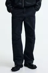 Pantalón estilo carpenter de corte holgado, confeccionado en tejido de algodón. Presenta tiro caído, bolsillos laterales de parche, trabilla funcional en una pierna y costuras reforzadas visibles sobre y debajo de las rodillas.