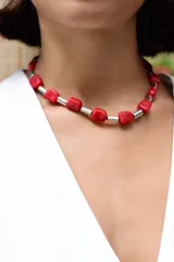 Collar tipo gargantilla compuesto por cuentas de piedra roja en forma irregular intercaladas con cilindros metálicos plateados. Cuenta con cadena de acero quirúrgico para ajustar el largo.