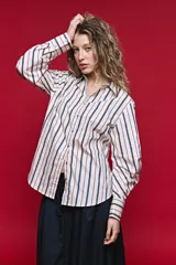 Camisa de algodón a rayas verticales en tonos azul, marrón y beige, con cuello camisero, cierre frontal de botones y mangas largas con puños estructurados y volumen.