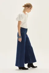 Jean de mezclilla azul oscuro, tiro alto, con pierna muy ancha (palazzo o wide leg) y costuras verticales marcadas en el frente.