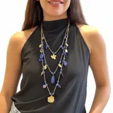 Collar largo de tres vueltas elaborado en acero, compuesto por una combinación de piedras naturales azules y dijes metálicos dorados con formas de flores y hojas.