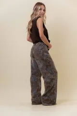 Jean de corte wide leg con estampado floral en tonos tierra sobre base de denim gris oscuro. Presenta tiro medio-alto, bolsillos traseros funcionales y costuras reforzadas.
