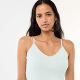 Musculosa celeste con tirantes finos, escote en V con detalle de encaje y pequeño lazo central, confeccionada en tejido texturizado.