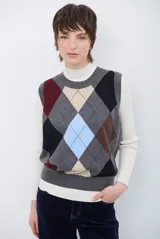 Chaleco de punto con diseño de rombos en tonos beige, marrón y gris. Presenta cuello redondo y corte ajustado a la cintura.