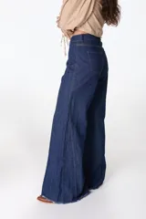 Pantalón de jean azul oscuro con corte wide leg, tiro alto y ruedo deshilachado. Presenta costuras verticales decorativas a lo largo de las piernas.