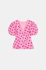 Top rosado con estampado de lunares fucsia, de cuello redondo y mangas cortas abullonadas con pliegues. Cuenta con escote en V en la espalda y cierre con cremallera oculta.
