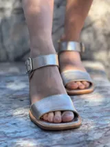 Sandalias de cuero color dorado con pulsera al tobillo y hebilla metálica. Taco bajo de madera.