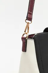 Cartera estructurada de símil cuero con diseño de bloques de color: principal en color camel, laterales en blanco y solapa frontal en negro. Posee correa larga regulable y desmontable.