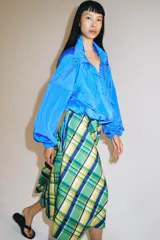 Falda midi de tiro medio marca ZWE Collection, confeccionada en hilatura de algodón con diseño de cuadros tipo tartán en tonos verdes, azules y amarillos. Tiene corte evasé y cierre lateral con cremallera oculta.