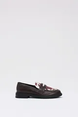 Mocasín de estilo clásico en color chocolate, confeccionado en cuero sintético liso con detalle de empeine en pelo sintético con estampado de manchas de vaca.