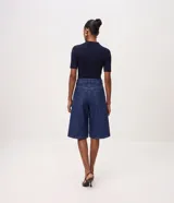 Bermuda long de jean azul con tiro alto, cintura con pasacintos, cierre con botón y cremallera, bolsillos funcionales y pespuntes en contraste.
