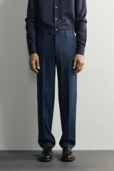 Pantalón de traje de corte regular fit en color azul marino, confeccionado en una mezcla de lino y lana. Cuenta con bolsillos delanteros, bolsillos traseros de doble vivo con botón y raya marcada en el centro de las piernas.