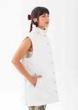 Chaleco acolchado de corte recto y largo medio, con diseño de rombos, cuello alto y cierre frontal con botones a presión.