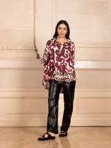 Camisa de manga corta con estampado abstracto en tonos azul marino, azul claro y blanco, y un patrón floral en el dobladillo.