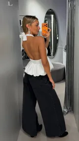 Top blanco con escote halter profundo y diseño peplum fluido, con corte ajustado en el busto y vuelo inferior.