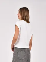 Remera blanca de manga corta y cuello redondo, con diseño holgado y hombros ligeramente caídos.