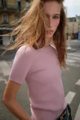 Jersey de punto color rosado claro, con cuello redondo y manga corta. Presenta una textura suave y un acabado ligeramente jaspeado.