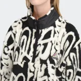 Campera de polar con diseño estampado en blanco y negro, cuello alto con medio cierre frontal y bolsillos laterales.