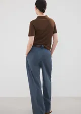 Chaleco de punto fino color marrón, de diseño recto, con cuello polo, mangas cortas y cierre delantero de botones.