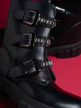 Botas negras de caña baja con suela track, cierre lateral y detalles de hebillas con tachas y cadenas.