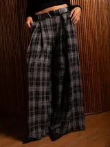 Pantalón tipo palazzo de tiro alto con diseño de cuadros tartán en tonos grises y negros. Presenta pinzas en la cintura, bolsillos laterales y corte amplio de pierna recta.