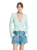 Blusa de tela plisada color verde menta, con escote en V cruzado, mangas largas acampanadas y lazos laterales para ajustar en la cintura.