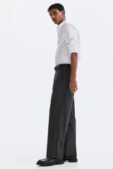 Pantalón de corte relajado en color gris oscuro, con cintura elástica, cierre de botón y cordón de ajuste oculto. Presenta raya marcada en las piernas, bolsillos laterales al bies y bolsillos traseros ribeteados con botón.
