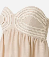 Blusa color beige sin breteles, confeccionada en viscolino con 15% de lino, con escote corazón, fruncidos y lastex en la espalda. La prenda tiene cuerditas aplicadas en el busto.