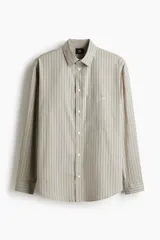 Camisa de popelina de algodón con diseño a rayas verticales en tonos beige y gris, cuello clásico, mangas largas y bolsillo frontal en el pecho.