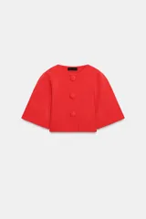 Chaqueta corta de punto color rojo, con cuello redondo, manga por debajo del codo y cierre frontal con botones forrados a tono.