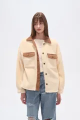 Campera tipo shacket de corderito color crema, con detalles en pana marrón en cuello, solapa de botones y bolsillos frontales. Diseño holgado de manga larga con cierre frontal de botones.