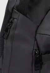 Mochila tipo bandolera de un solo hombro, color tostado, con correas ajustables negras y cierre frontal.