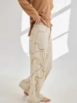 Pantalon de corte recto y tiro medio, color beige, con bordados artesanales en hilo que simulan vetas. Confeccionado en una mezcla de algodón, viscosa y lino.